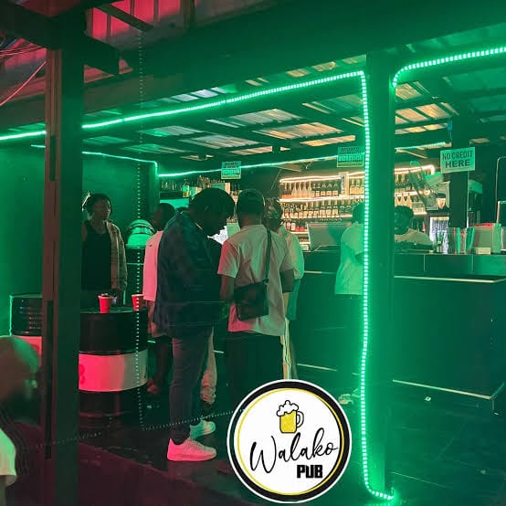 Green neon-lit bar counter at Walako Pub